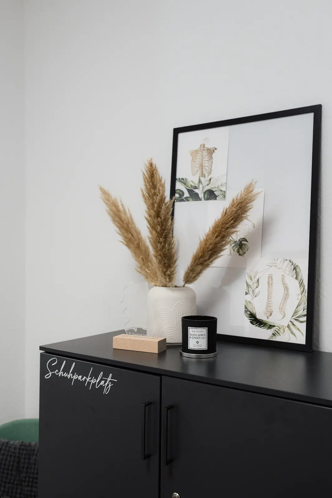 Dekoratives Detail im Empfangsbereich – Vase mit Pampasgras und gerahmte Illustration
